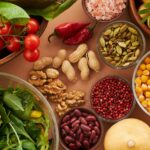 Explore a colorful assortment of healthy ingredients, featuring vegetables, nuts, seeds, and spices in a top view layout.
