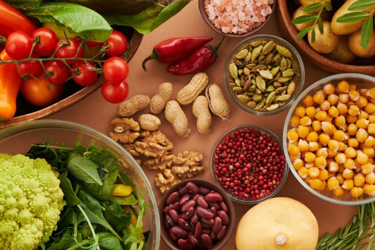 Explore a colorful assortment of healthy ingredients, featuring vegetables, nuts, seeds, and spices in a top view layout.