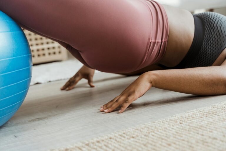Close-up of a woman working out indoors using a fitness ball. Focus on balance and core strength.