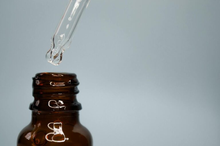 Close-up of a glass dropper with an amber bottle against a neutral background.