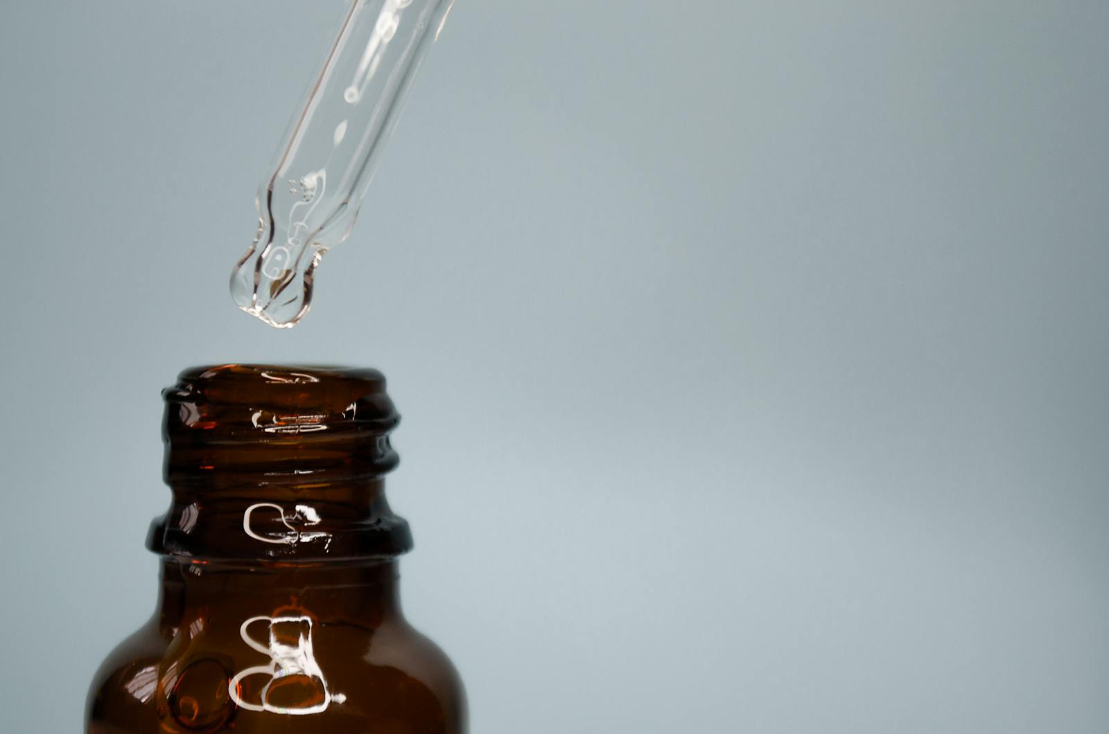 Close-up of a glass dropper with an amber bottle against a neutral background.