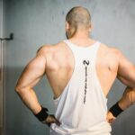 A muscular man from behind showcasing strength and fitness in a gym setting.