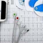 Close-up of ECG device with leads and electrodes on printed heart rate graph, showcasing medical technology.