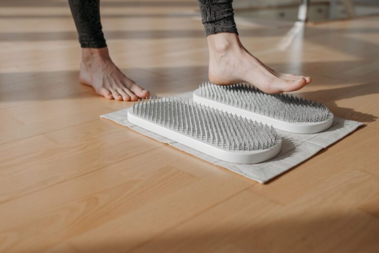 Close-up of a person using acupressure mats on a wooden floor, promoting relaxation and health.