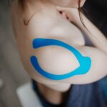 Close-up of a shoulder with kinesiology tape applied for muscle support during sports activities.