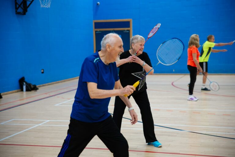 Seniors playing badminton in a gymnasium