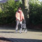Elderly person with walker on a paved path