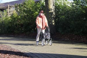 Elderly person with walker on a paved path